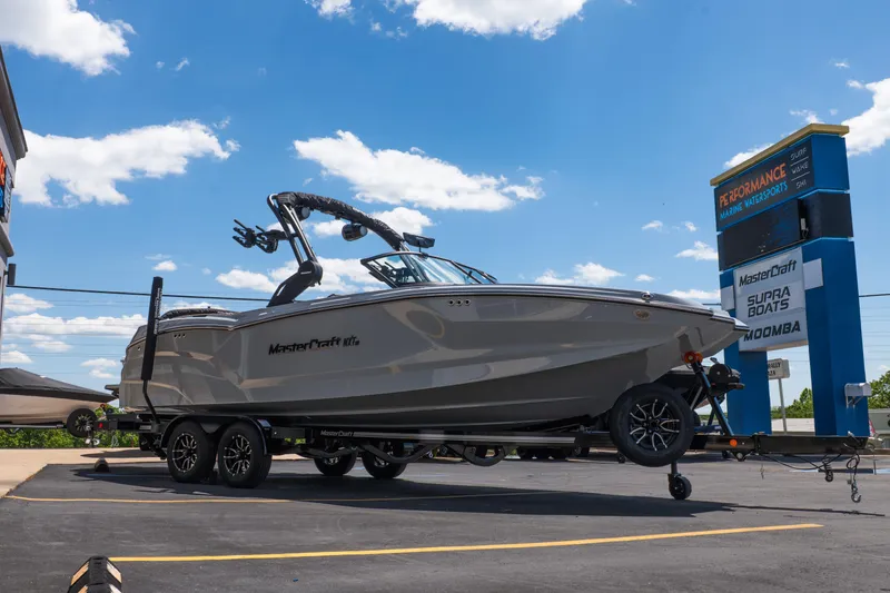 Slide: The Image of 2026 MasterCraft NXT24 boat on trailer at dealership under blue sky. - 11