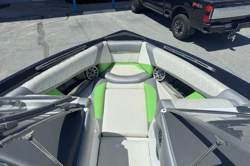 Slide: The Image of 2015 Tigé Z1 boat interior with green and white seating, parked on pavement. - 8