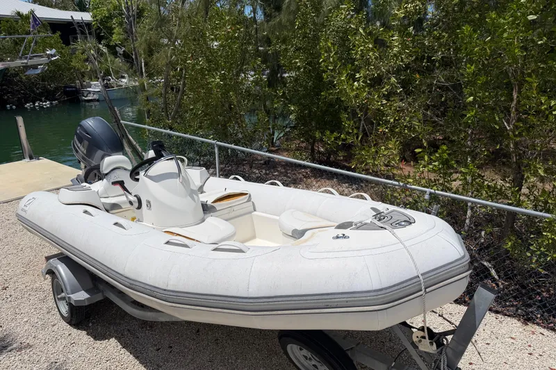 The Image of 2021 Zodiac Yachtline 440 inflatable boat on trailer, surrounded by lush greenery. - 1