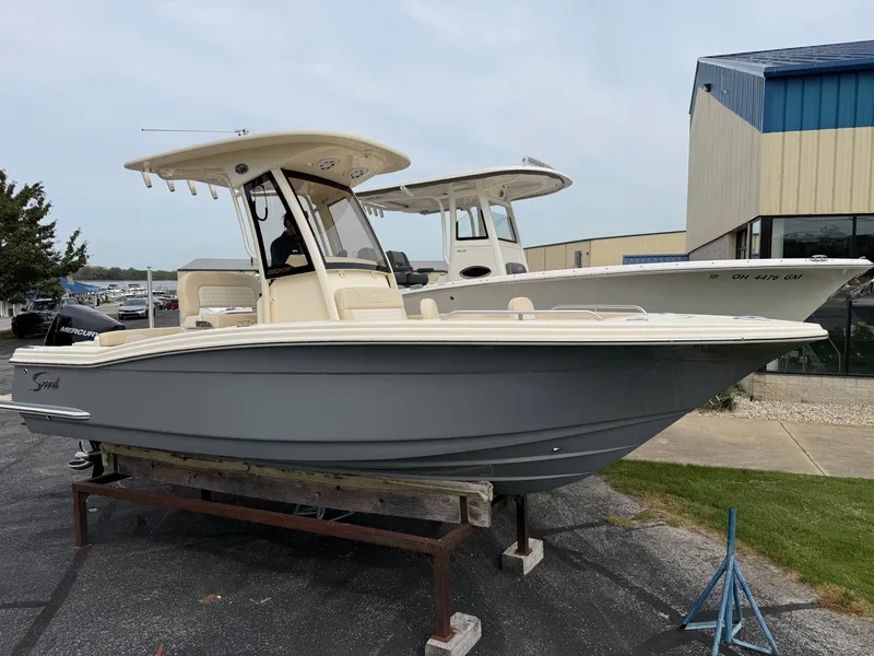 The Image of A 2027 Scout 220 XSF boat is on a stand in a marina area. - 0