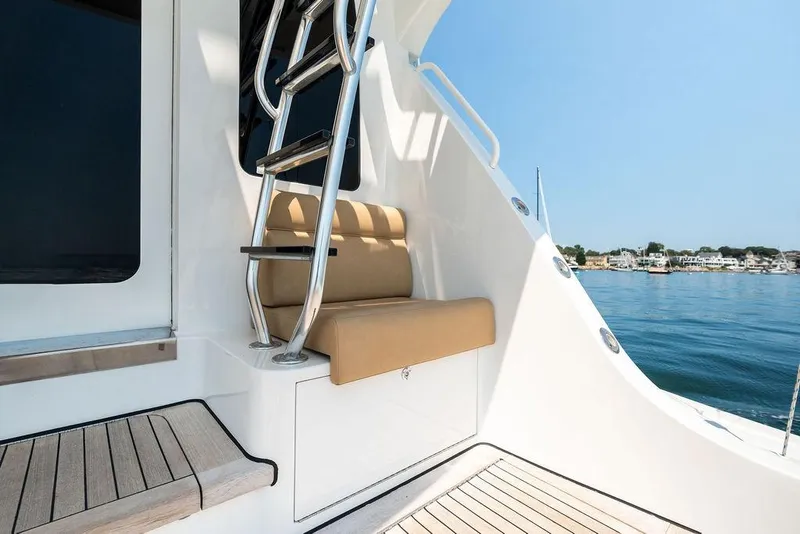 Slide: The Image of 2006 Hatteras 68 Convertible yacht deck with ladder and seating, overlooking serene waters. - 18