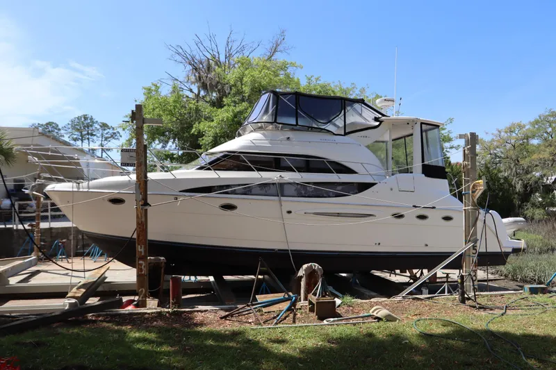 The Image of 2005 Meridian 459 Motoryacht on dry dock, surrounded by trees and equipment. - 0