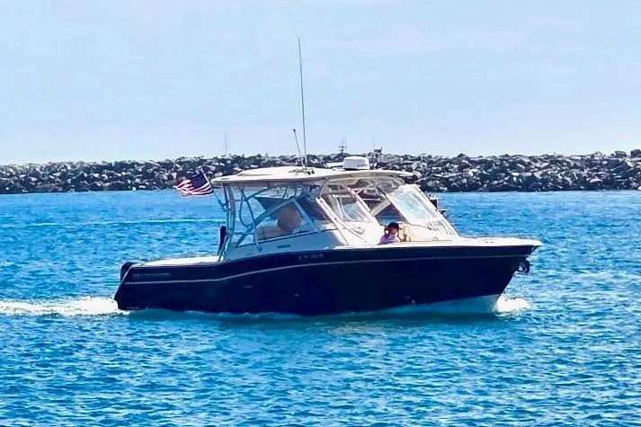 Slide: The Image of 2014 Grady-White Freedom 335 boat cruising on blue water near rocky shoreline. - 15