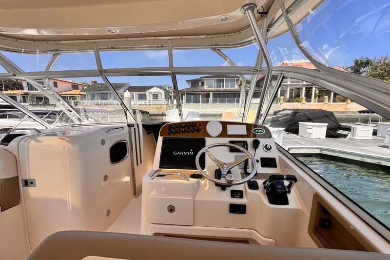 Slide: The Image of 2014 Grady-White Freedom 335 boat cockpit with Garmin navigation, docked near waterfront homes. - 35