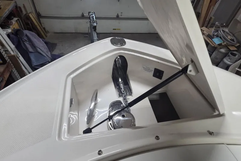 Slide: The Image of 2019 Regal 29 OBX boat anchor compartment with open hatch in a garage setting. - 17