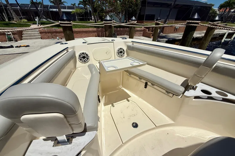 Slide: The Image of 2023 Scout 255 LXF boat interior with seating and table, docked near water. - 16