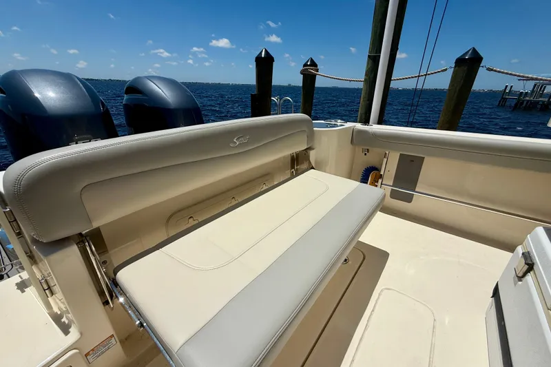 Slide: The Image of 2023 Scout 255 LXF boat interior with seating and dual engines, docked by the water. - 25