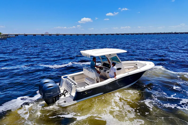 Slide: The Image of 2023 Scout 255 LXF boat cruising on open water under a clear blue sky. - 6