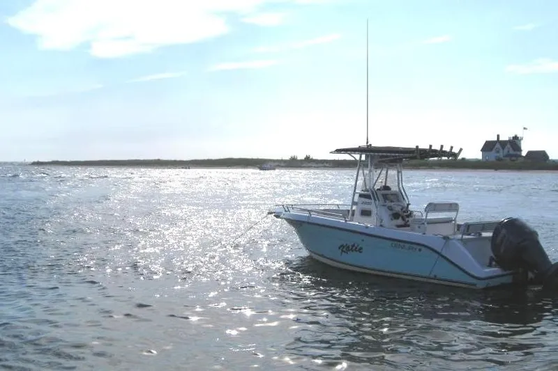 Slide: The Image of Century 2200 Center Console boat on shimmering water, 2004 model, near a coastal house. - 4