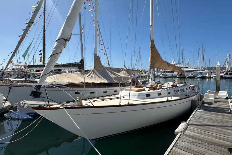 The Image of 1966 CAL Cal 48 sailboat docked at marina, surrounded by other boats under clear blue sky. - 0