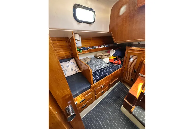 Slide: The Image of Cozy cabin interior of 1966 CAL Cal 48 sailboat with wooden furnishings and striped cushions. - 13