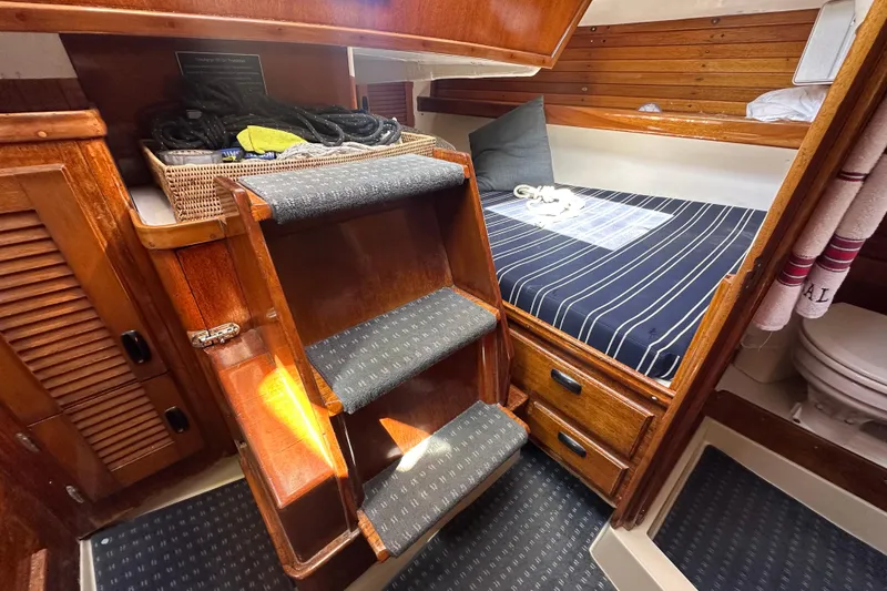 Slide: The Image of Cozy cabin interior of 1966 CAL 48 sailboat with wooden stairs and striped bedding. - 15