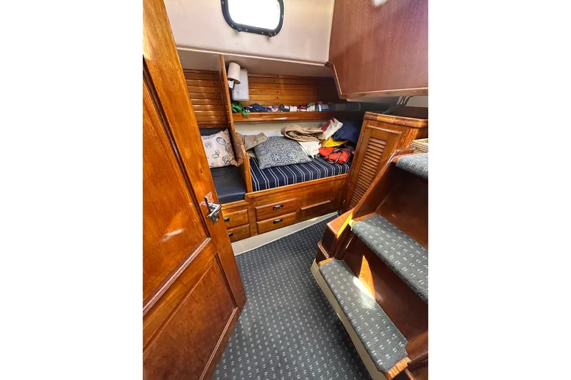 Slide: The Image of Cozy cabin interior of 1966 CAL Cal 48 sailboat with wooden furnishings and striped bedding. - 16