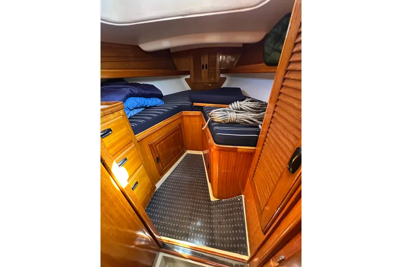 Slide: The Image of Cozy cabin interior of 1966 CAL Cal 48 sailboat with wooden furnishings and striped bedding. - 20