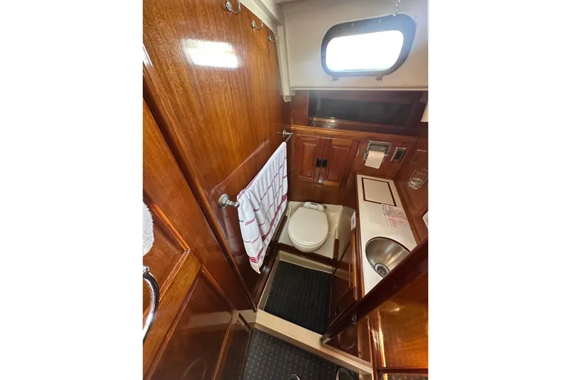 Slide: The Image of 1966 CAL Cal 48 yacht bathroom with wooden cabinetry, sink, and porthole window. - 22