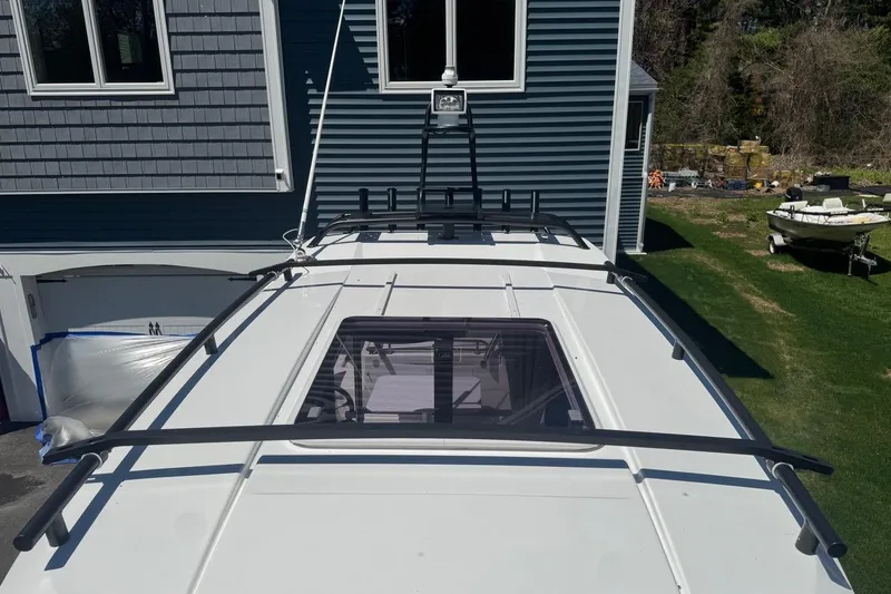 Slide: The Image of 2023 Jeanneau NC Sport 695 Series 2 boat roof with railing, parked near a house. - 31
