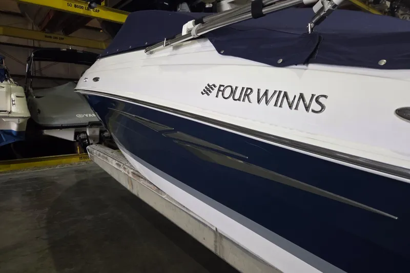 Slide: The Image of 2014 Four Winns 190 Horizon boat in storage, featuring sleek blue and white design. - 10