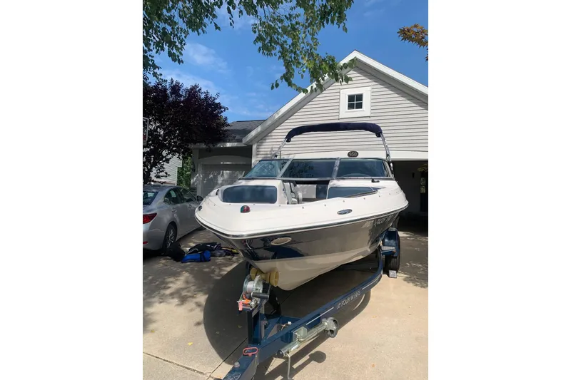 Slide: The Image of 2014 Four Winns 190 Horizon boat on trailer in driveway, under clear blue sky. - 4