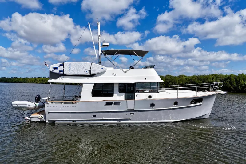 The Image of 2020 Beneteau Swift Trawler 44 cruising on a calm river under a blue sky. - 1
