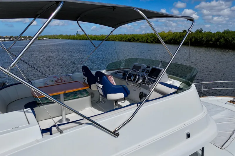 Slide: The Image of Flybridge of 2020 Beneteau Swift Trawler 44 with seating and navigation controls on a sunny day. - 11