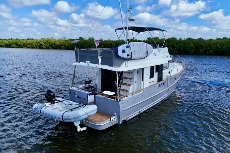 Slide: The Image of 2020 Beneteau Swift Trawler 44 cruising on a scenic river under a blue sky. - 12