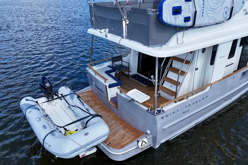 Slide: The Image of Beneteau Swift Trawler 44, 2020 model, docked with inflatable boat on water. - 13