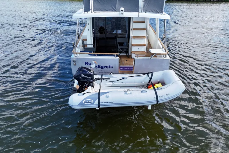 Slide: The Image of Beneteau Swift Trawler 44, 2020 model, with dinghy on water. - 14