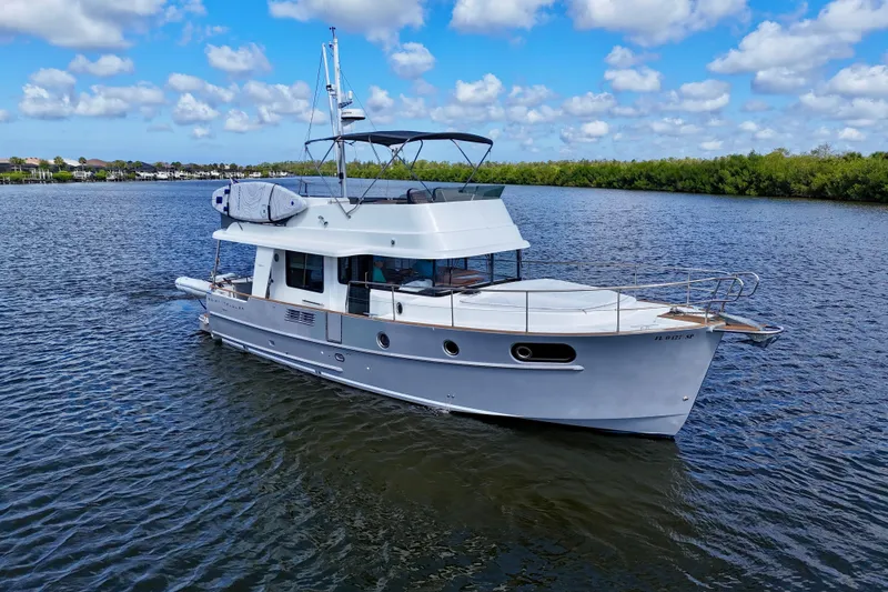 Slide: The Image of 2020 Beneteau Swift Trawler 44 cruising on a serene lake under a blue sky. - 16