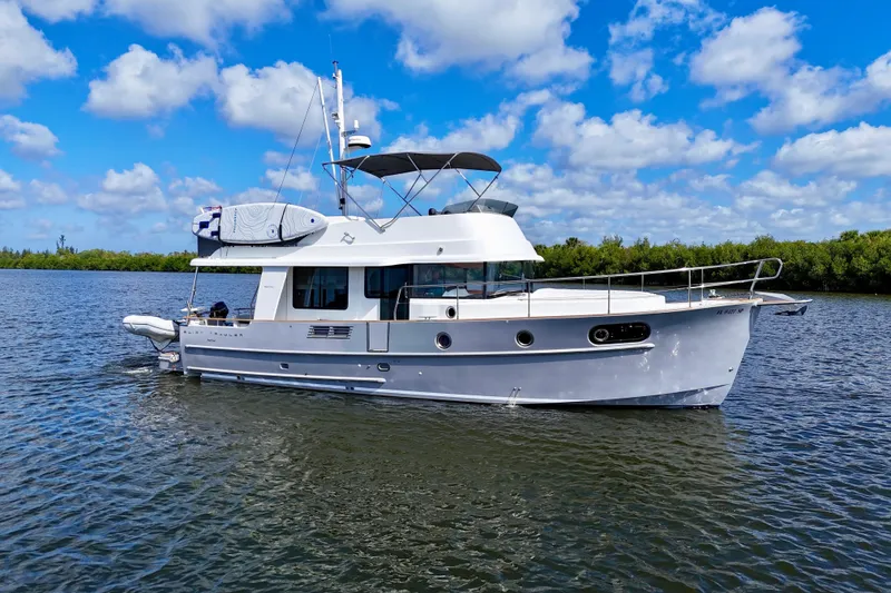 Slide: The Image of 2020 Beneteau Swift Trawler 44 cruising on a calm river under a blue sky. - 18