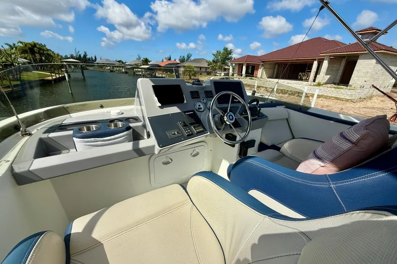 Slide: The Image of 2020 Beneteau Swift Trawler 44 helm with plush seating, overlooking serene waterfront homes. - 25