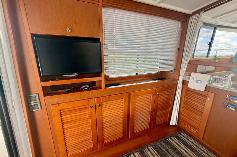 Slide: The Image of Interior of 2020 Beneteau Swift Trawler 44 with TV, wooden cabinets, and window blinds. - 47