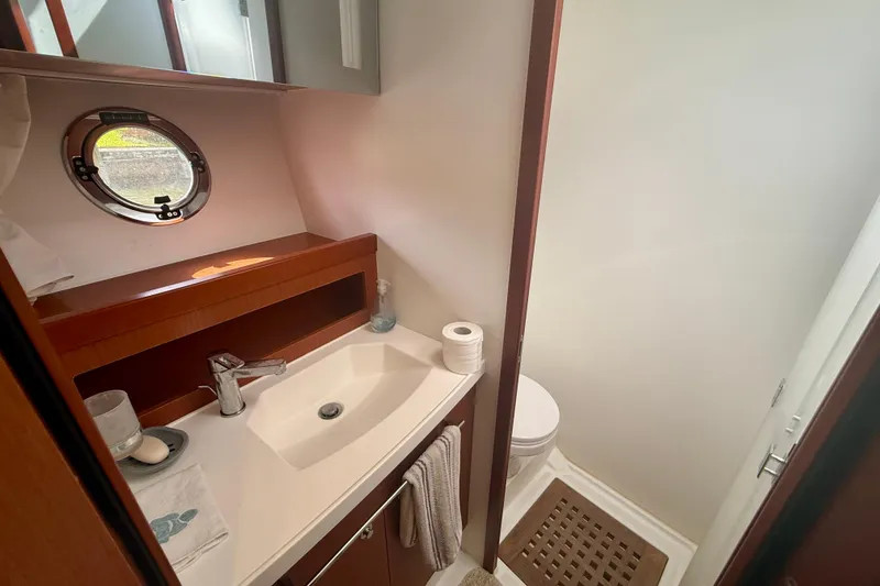 Slide: The Image of Bathroom interior of 2020 Beneteau Swift Trawler 44, featuring sink, toilet, and porthole window. - 58