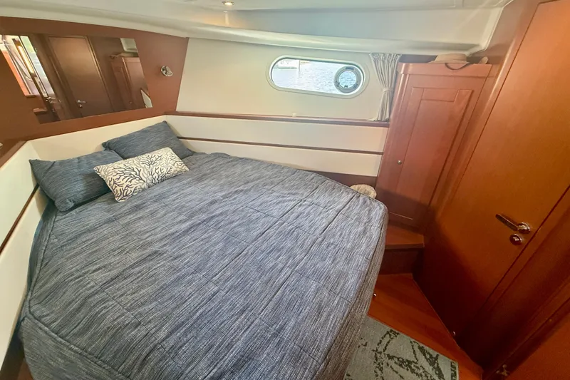 Slide: The Image of Cozy bedroom in 2020 Beneteau Swift Trawler 44 with blue bedding and wooden accents. - 60
