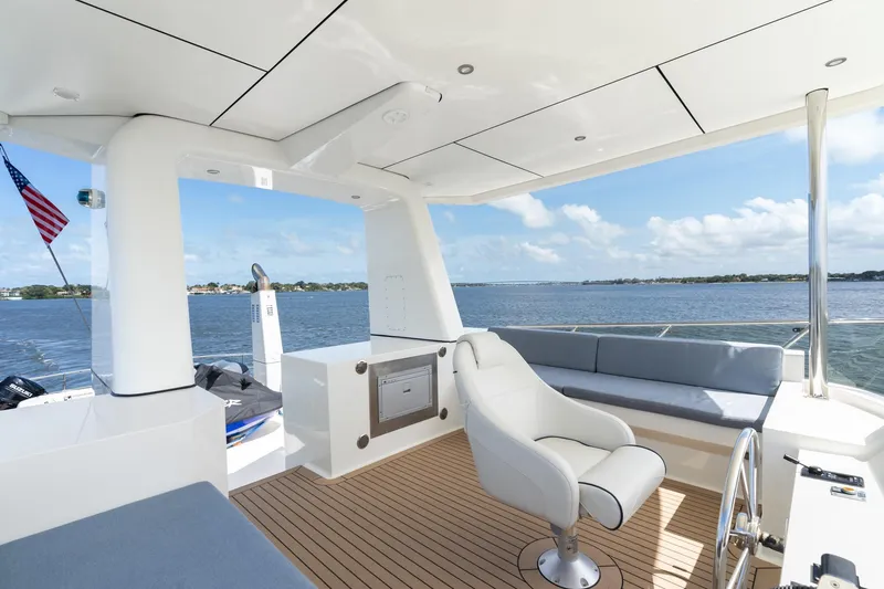 Slide: The Image of Luxurious 2022 Alm Trawler Delfino 64 yacht deck with seating, overlooking serene waters. - 13