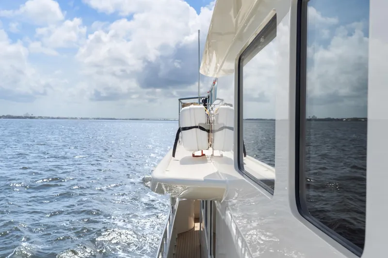 Slide: The Image of Side view of 2022 Alm Trawler Delfino 64 yacht cruising on open water. - 22