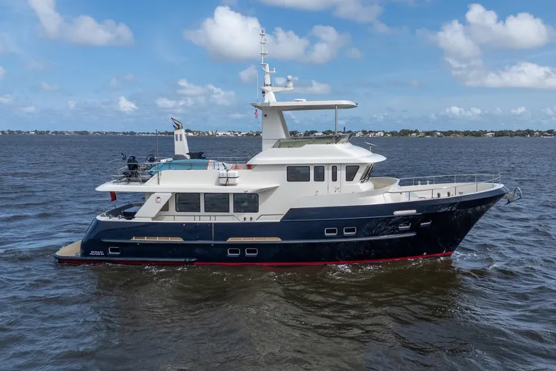 Slide: The Image of 2022 Alm Trawler Delfino 64 yacht cruising on open water under a clear blue sky. - 4