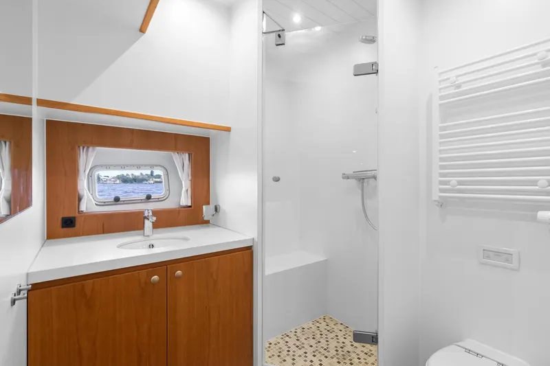 Slide: The Image of Modern bathroom interior on 2022 Alm Trawler Delfino 64 yacht, featuring sleek design and wood accents. - 53