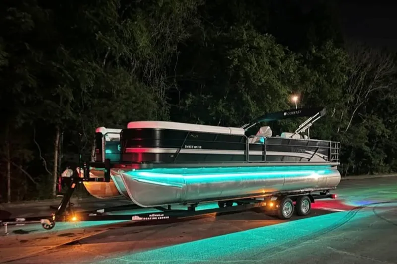 The Image of 2023 Godfrey Sweetwater 2486 SFL pontoon boat with vibrant underglow lights at night. - 0