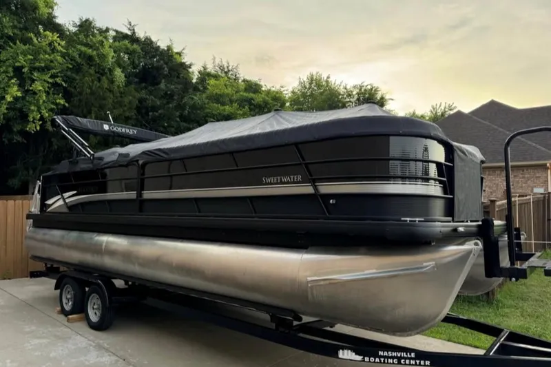 Slide: The Image of 2023 Godfrey Sweetwater 2486 SFL pontoon boat on trailer, covered and parked outdoors. - 2