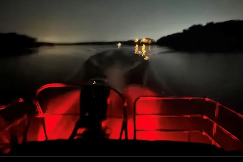 Slide: The Image of 2023 Godfrey Sweetwater 2486 SFL boat cruising at night with red interior lights. - 4