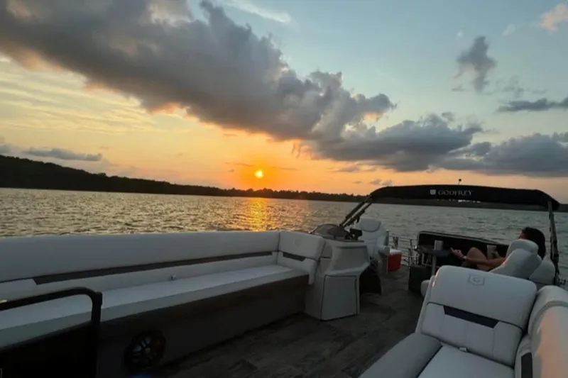 Slide: The Image of 2023 Godfrey Sweetwater 2486 SFL pontoon boat at sunset on a serene lake. - 6