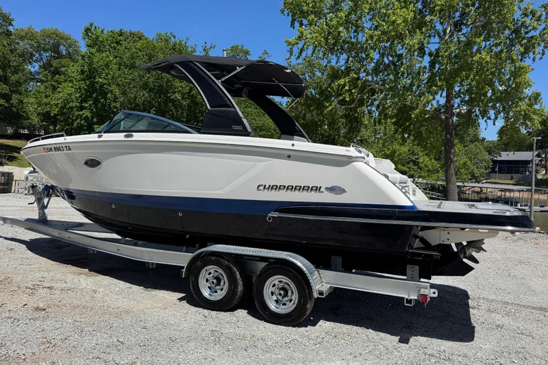 Slide: The Image of 2021 Chaparral 287 SSX boat on trailer, parked outdoors with trees in background. - 3