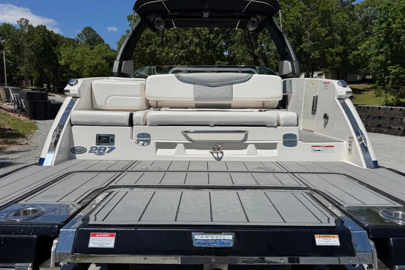 Slide: The Image of 2021 Chaparral 287 SSX boat with spacious rear deck and seating, surrounded by greenery. - 5