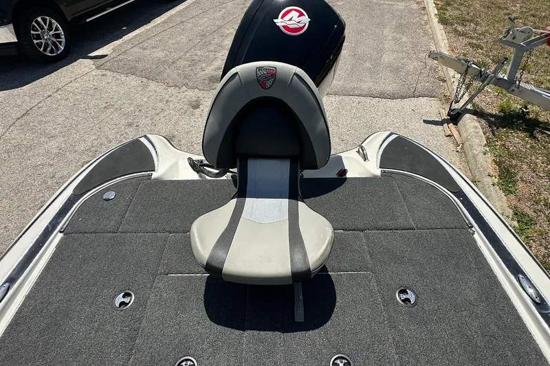 Slide: The Image of 2026 Triton 179 TrX boat with cushioned seat and motor, parked on pavement. - 19
