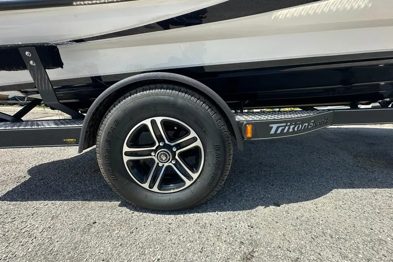 Slide: The Image of Trailer wheel of 2026 Triton 179 TrX boat on asphalt surface. - 29