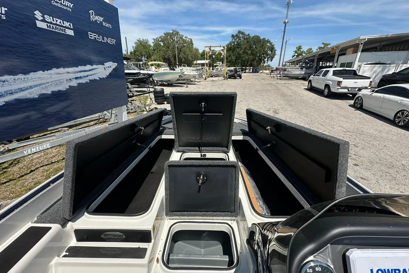 Slide: The Image of 2026 Triton 179 TrX boat with open storage compartments, displayed outdoors on a sunny day. - 7
