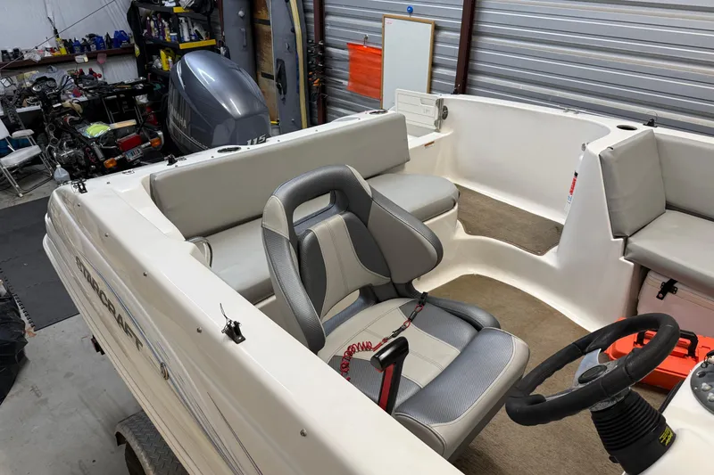 Slide: The Image of 2014 Starcraft 1915 OB Limited boat interior with seating and steering wheel in a garage. - 11