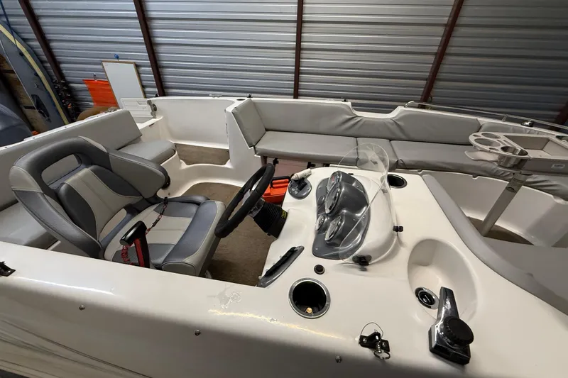 Slide: The Image of 2014 Starcraft 1915 OB Limited boat interior with steering wheel and seating in storage. - 12