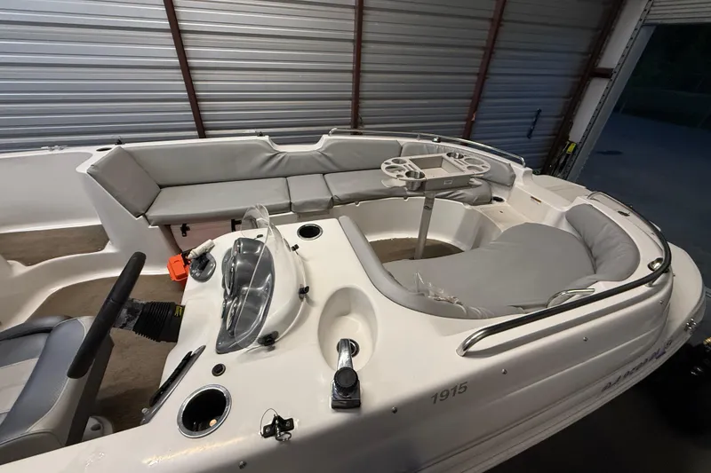 Slide: The Image of 2014 Starcraft 1915 OB Limited boat interior with seating and steering wheel in a garage. - 14