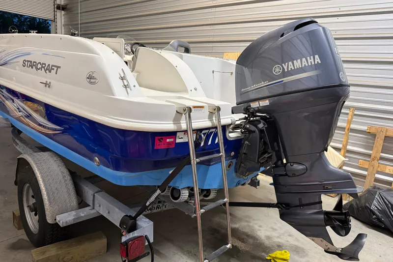 Slide: The Image of 2014 Starcraft 1915 OB Limited boat with Yamaha outboard motor on trailer in garage. - 8